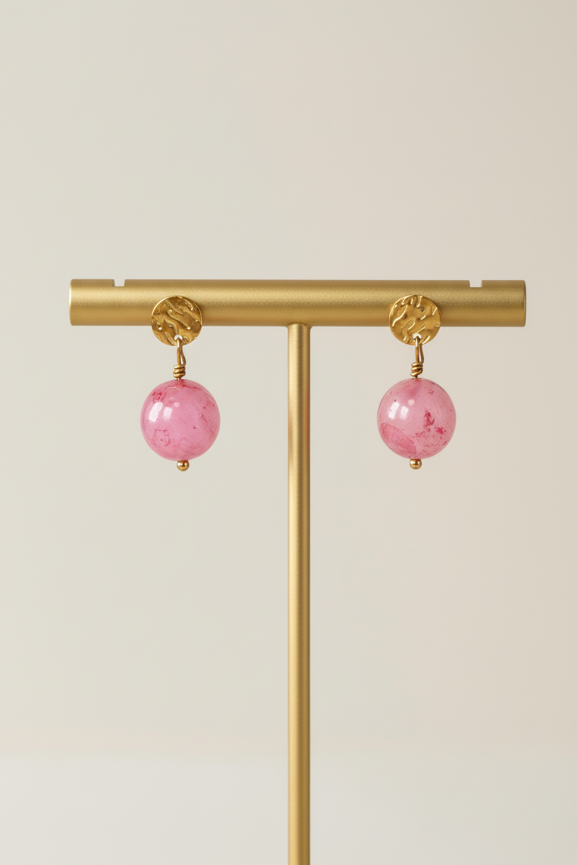 Lyserøde perleøreringe på guldstativ